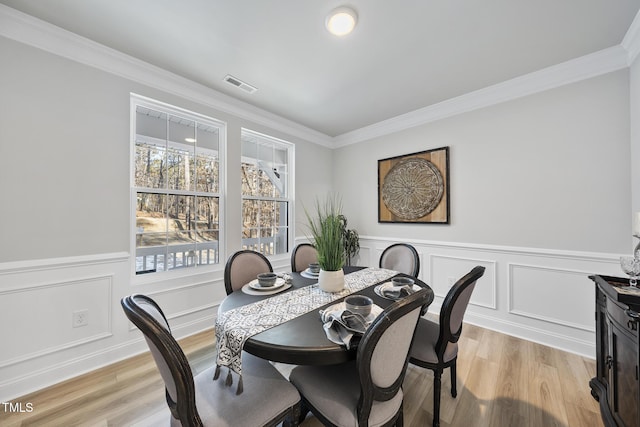 dining space with crown molding and light hardwood / wood-style floors