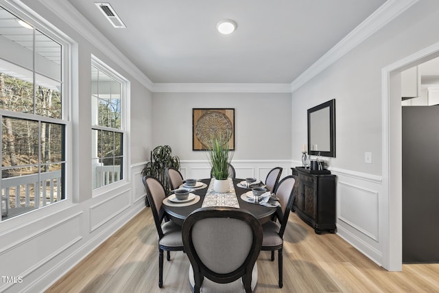 dining area with crown molding and light hardwood / wood-style floors