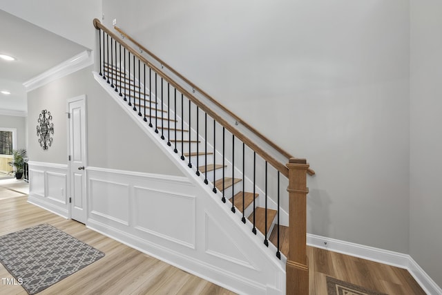 staircase featuring ornamental molding and hardwood / wood-style floors