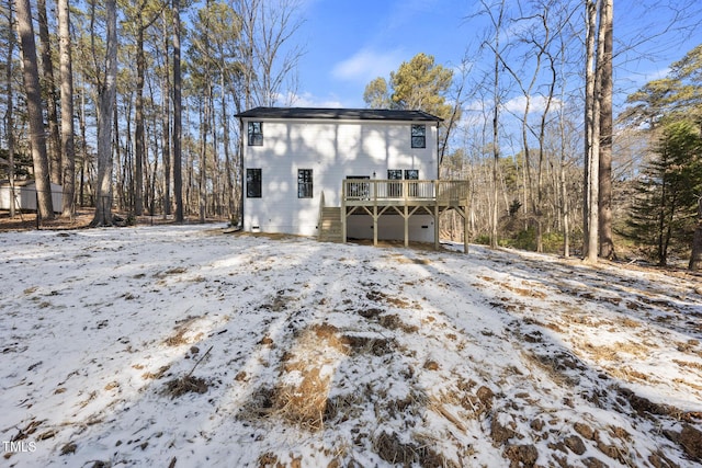 snow covered back of property featuring a deck