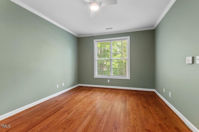 spare room featuring baseboards, ornamental molding, ceiling fan, and wood finished floors