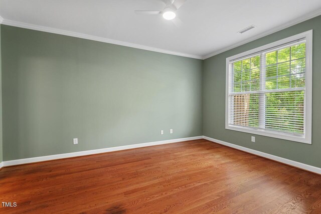 unfurnished room featuring ceiling fan, visible vents, crown molding, wood finished floors, and baseboards