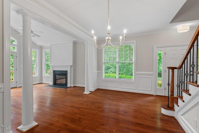 unfurnished living room with crown molding, a fireplace with flush hearth, wood finished floors, stairway, and a wainscoted wall