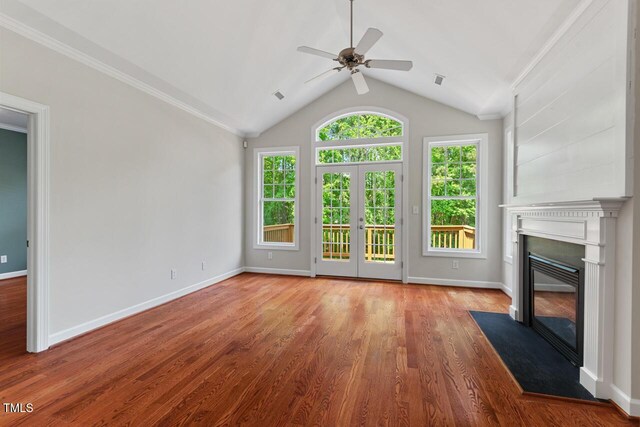 unfurnished living room with a ceiling fan, baseboards, a fireplace with flush hearth, wood finished floors, and vaulted ceiling