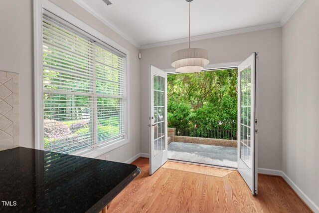 doorway to outside with baseboards, ornamental molding, and wood finished floors
