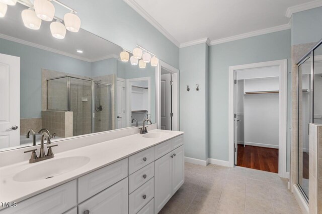 bathroom with crown molding, a sink, a stall shower, and a spacious closet
