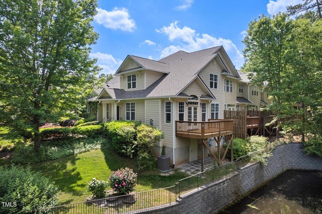 back of property with fence, a deck, a shingled roof, central air condition unit, and a yard