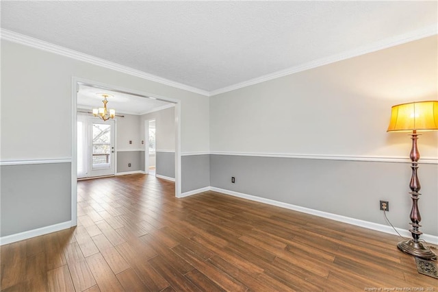 empty room with a notable chandelier, ornamental molding, and dark hardwood / wood-style flooring