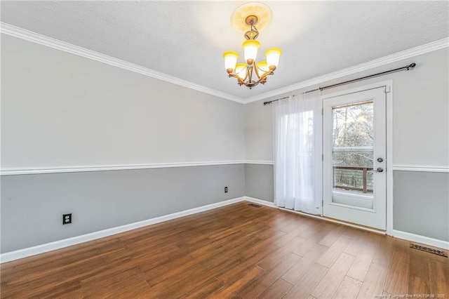 spare room featuring a textured ceiling, hardwood / wood-style flooring, a chandelier, and ornamental molding