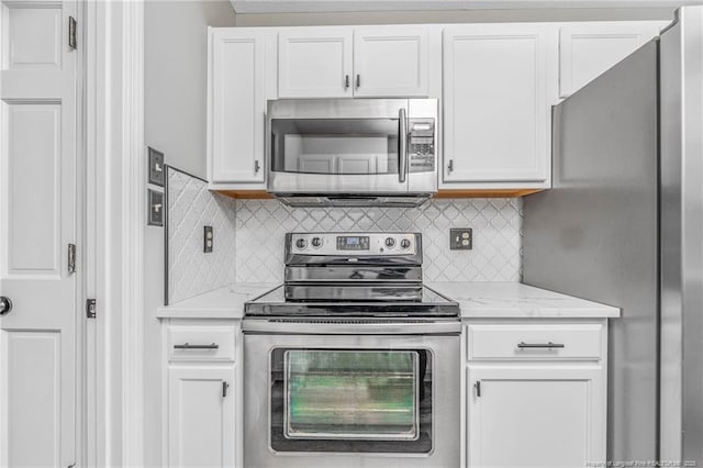 kitchen featuring white cabinets, stainless steel appliances, light stone countertops, and decorative backsplash