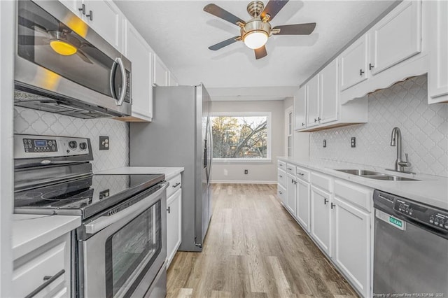 kitchen featuring white cabinetry, stainless steel appliances, sink, ceiling fan, and light hardwood / wood-style flooring