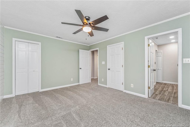 unfurnished bedroom with ceiling fan, carpet, crown molding, and a textured ceiling