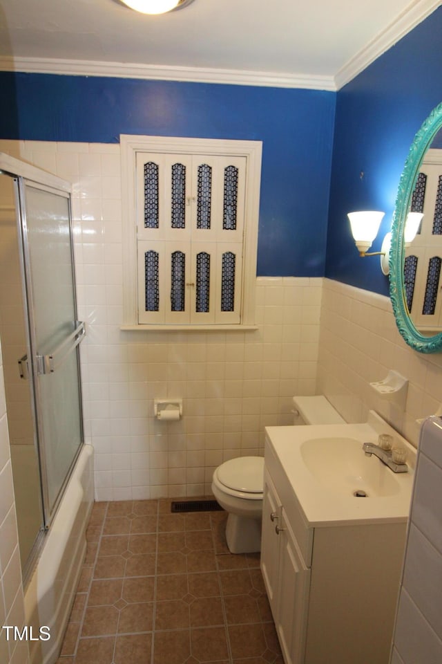 full bathroom with enclosed tub / shower combo, tile patterned floors, tile walls, toilet, and crown molding