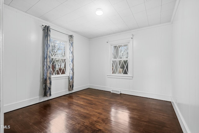 unfurnished room with dark hardwood / wood-style floors, a wealth of natural light, and ornamental molding