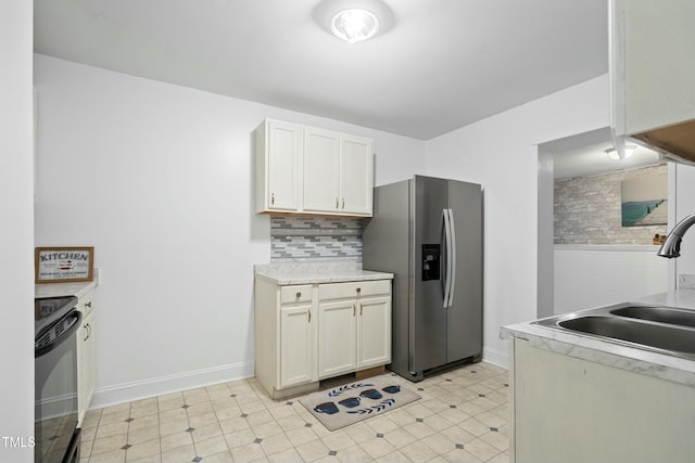 kitchen with white cabinets, black range with electric stovetop, sink, backsplash, and stainless steel fridge