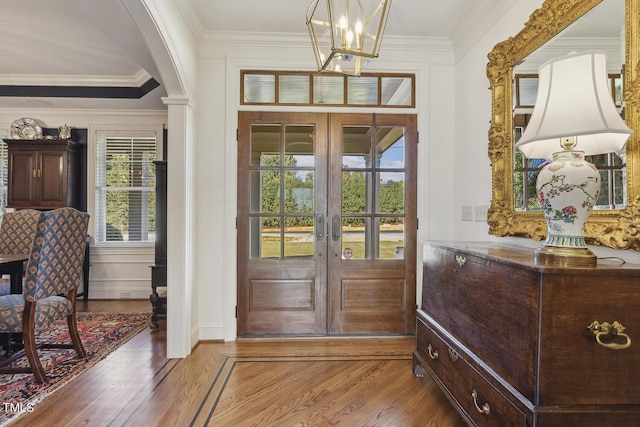 foyer entrance with hardwood / wood-style flooring, ornamental molding, a chandelier, and french doors