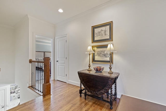 hallway with ornamental molding and light hardwood / wood-style flooring