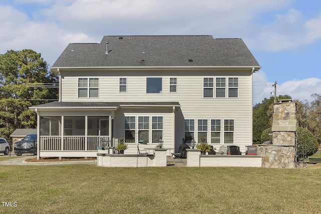 back of house with a fireplace, a yard, a patio area, and a sunroom