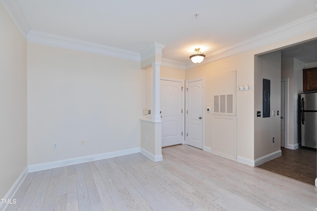 unfurnished room featuring crown molding, electric panel, decorative columns, and light wood-type flooring