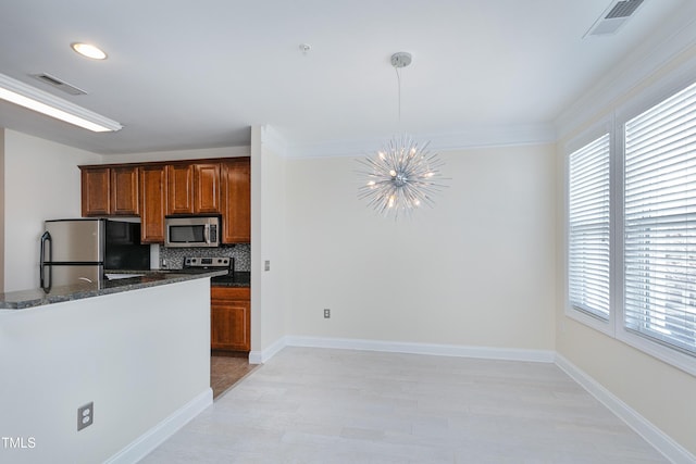 kitchen with pendant lighting, dark stone countertops, backsplash, stainless steel appliances, and a chandelier