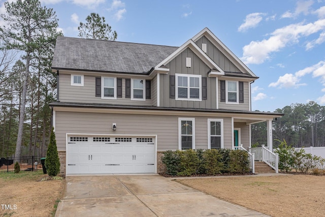 craftsman house with an attached garage, driveway, fence, and board and batten siding