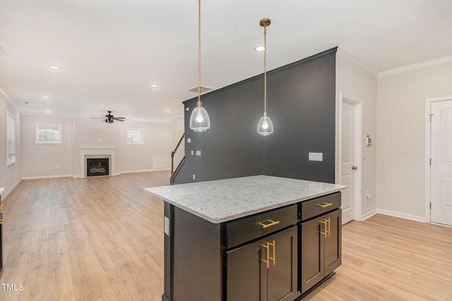 kitchen featuring a fireplace with flush hearth, ceiling fan, light wood-style flooring, crown molding, and pendant lighting