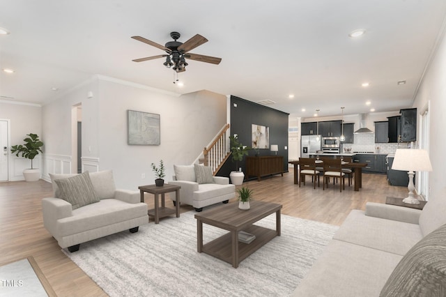 living area with a ceiling fan, stairway, crown molding, light wood-type flooring, and recessed lighting