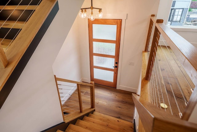 stairs featuring hardwood / wood-style floors and an inviting chandelier