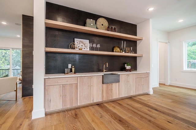 bar featuring plenty of natural light, sink, light brown cabinets, and light hardwood / wood-style floors