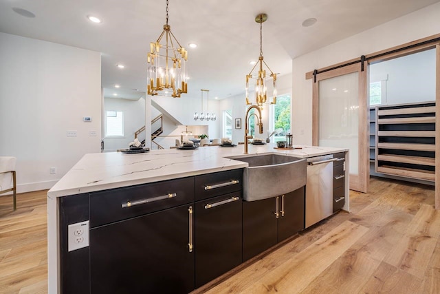 kitchen with a spacious island, sink, hanging light fixtures, stainless steel dishwasher, and a barn door