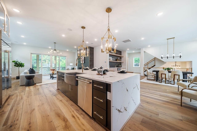 kitchen with pendant lighting, sink, appliances with stainless steel finishes, a spacious island, and light hardwood / wood-style floors