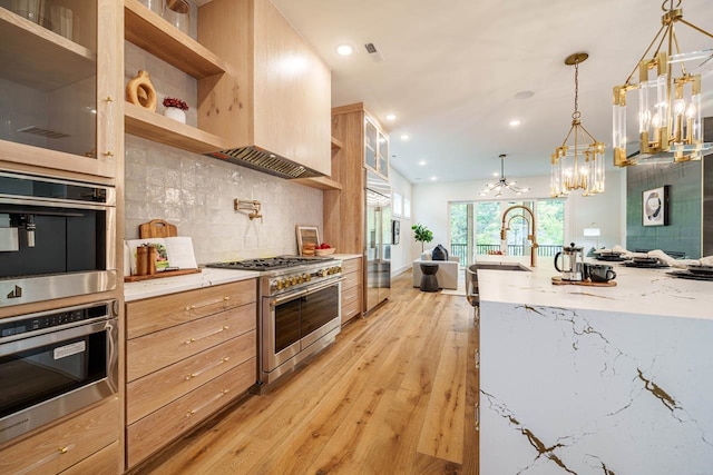 kitchen featuring pendant lighting, high quality appliances, sink, backsplash, and light stone counters