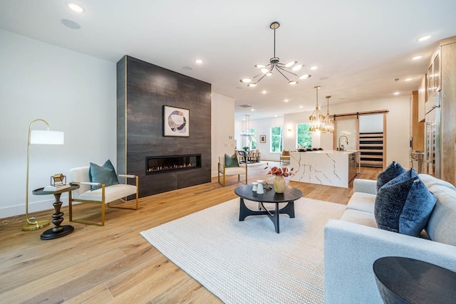 living room featuring a fireplace, a chandelier, sink, and light wood-type flooring