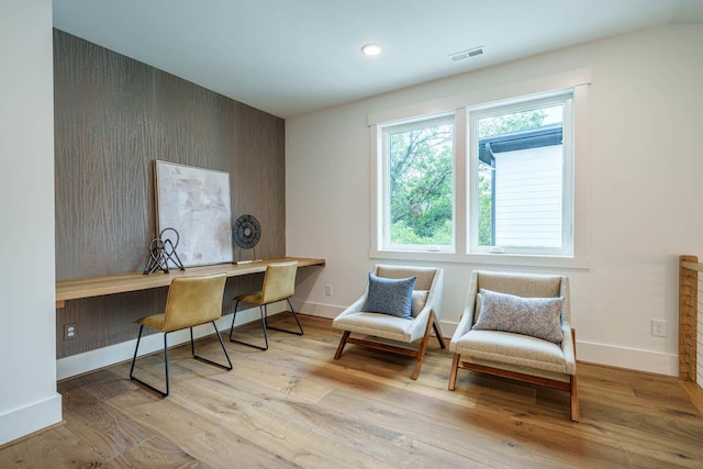 office space with built in desk and light wood-type flooring