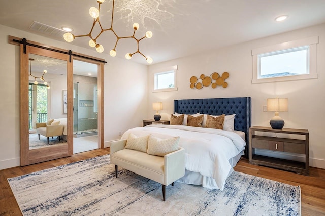 bedroom with hardwood / wood-style flooring, ensuite bathroom, and a barn door