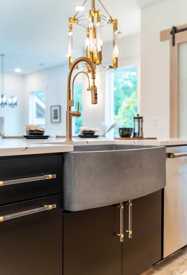 kitchen featuring dishwasher, a barn door, a notable chandelier, and decorative light fixtures