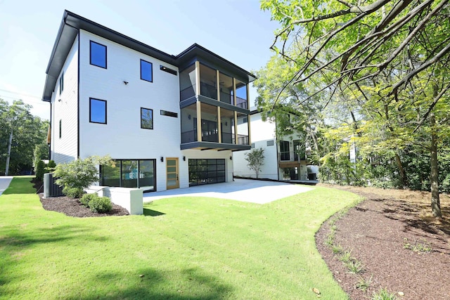 rear view of house featuring central AC unit and a lawn