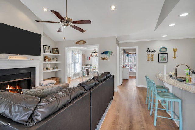 living room with lofted ceiling, sink, ceiling fan, crown molding, and light hardwood / wood-style flooring