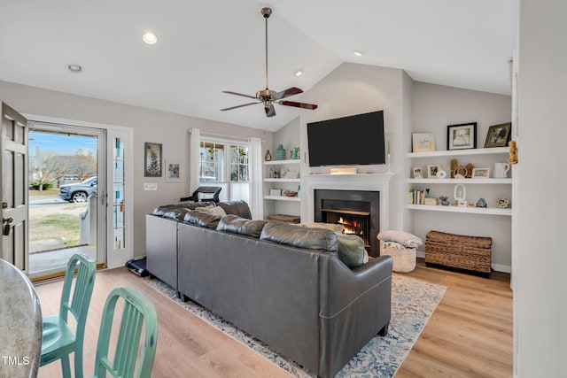 living room with ceiling fan, lofted ceiling, and light hardwood / wood-style floors