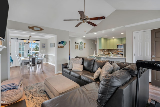 living room with vaulted ceiling, sink, ceiling fan with notable chandelier, and light hardwood / wood-style floors