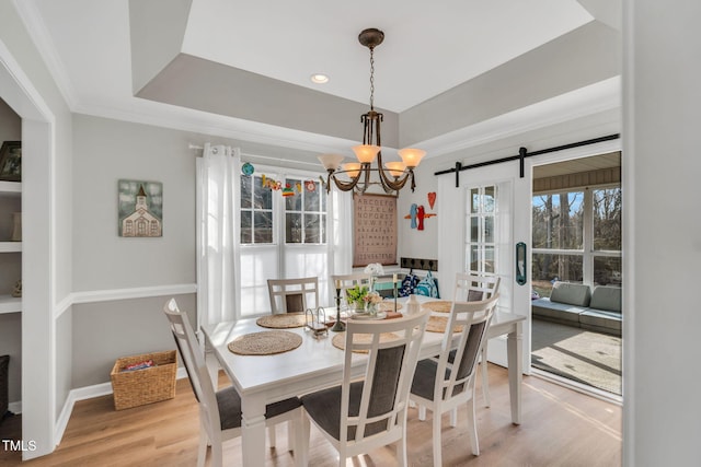 dining room featuring a chandelier, crown molding, a raised ceiling, and light hardwood / wood-style floors