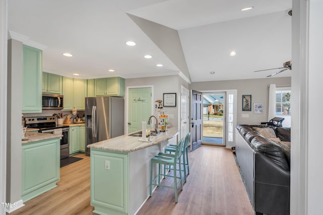 kitchen featuring vaulted ceiling, appliances with stainless steel finishes, a breakfast bar, sink, and green cabinetry