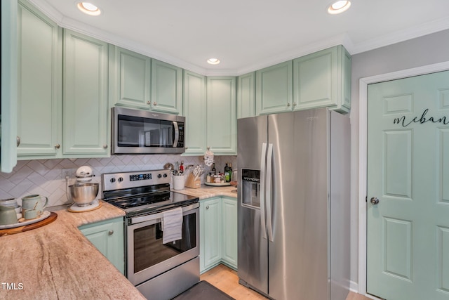 kitchen with stainless steel appliances, light stone counters, ornamental molding, green cabinetry, and decorative backsplash