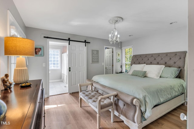 bedroom with light hardwood / wood-style flooring, a barn door, and a chandelier