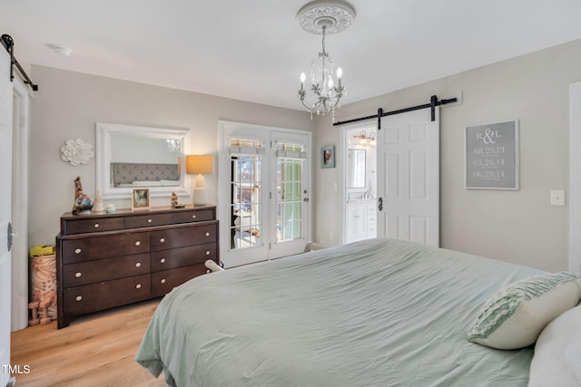 bedroom featuring a barn door, light hardwood / wood-style floors, and access to exterior