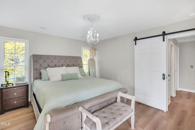 bedroom with a notable chandelier, a barn door, and light wood-type flooring