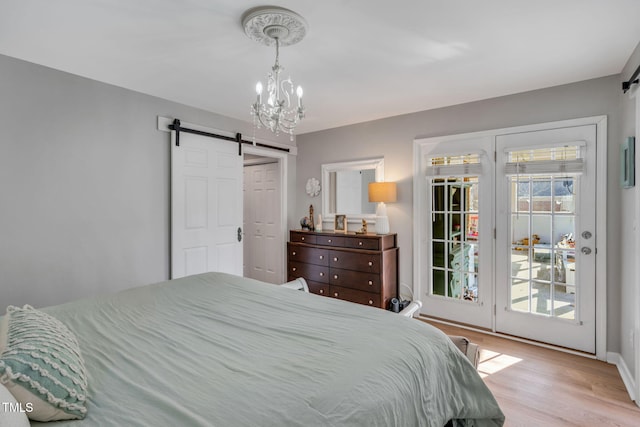 bedroom with a barn door, a chandelier, access to outside, and light wood-type flooring