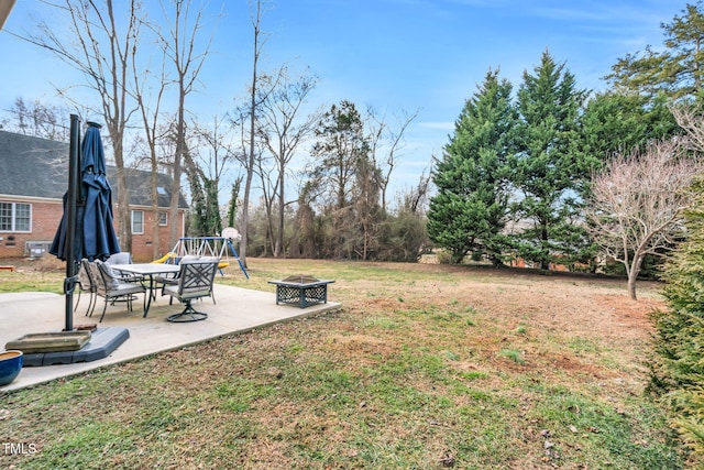 view of yard featuring a playground, a patio area, and an outdoor fire pit