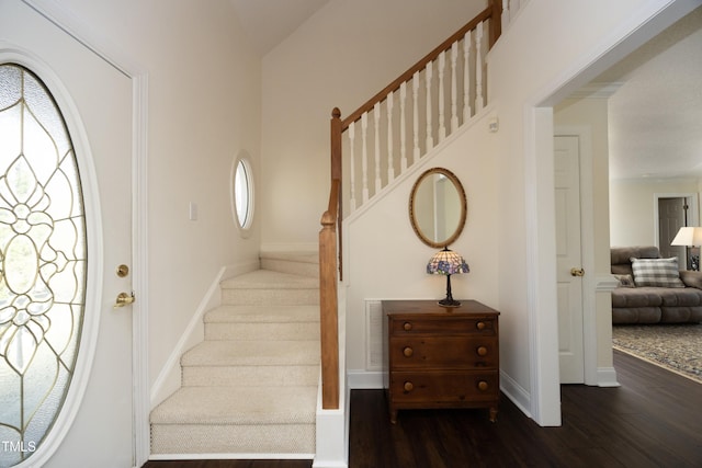 foyer entrance with baseboards, wood finished floors, and stairs