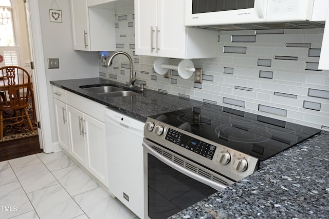 kitchen with dark stone countertops, white cabinets, marble finish floor, white appliances, and a sink